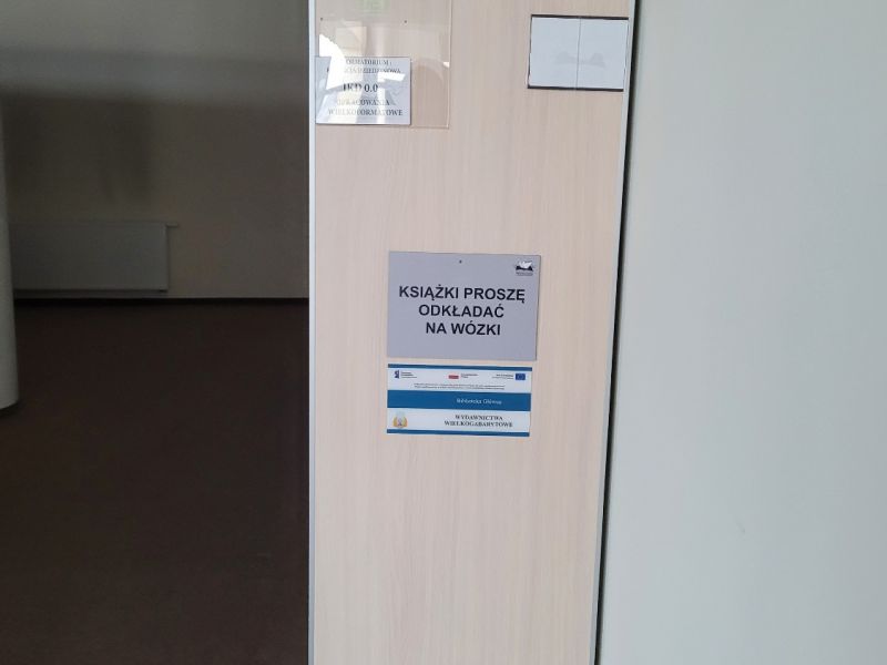 Tabliczka informacyjna na regale z książkami Tabliczka informacyjna na regale z książkami