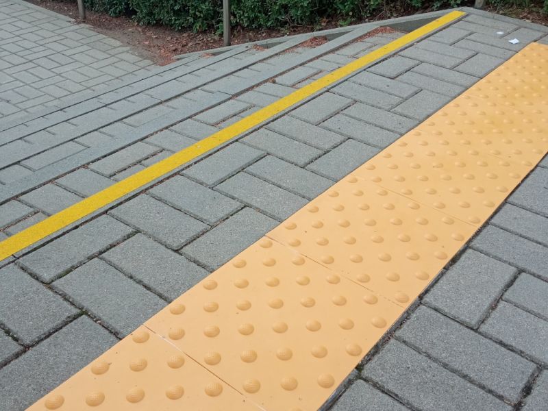 Pole uwagi i kontrastowe oznaczenie schodów na zewnątrz budynku Pole uwagi i kontrastowe oznaczenie schodów na zewnątrz budynku