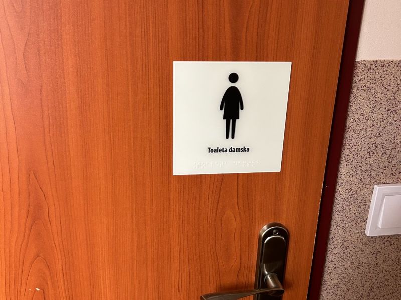 Tabliczka informacyjna w brajlu i czarnym druku z piktogramem, na drzwi Tabliczka informacyjna w brajlu i czarnym druku z piktogramem, na drzwi